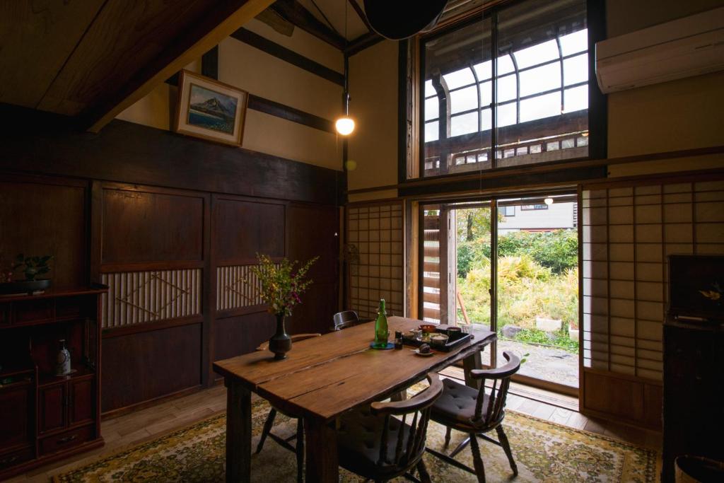 Cette chambre dispose d'une table en bois et d'une grande fenêtre. dans l'établissement Noka Minshuku Sanzen, à Tōkamachi
