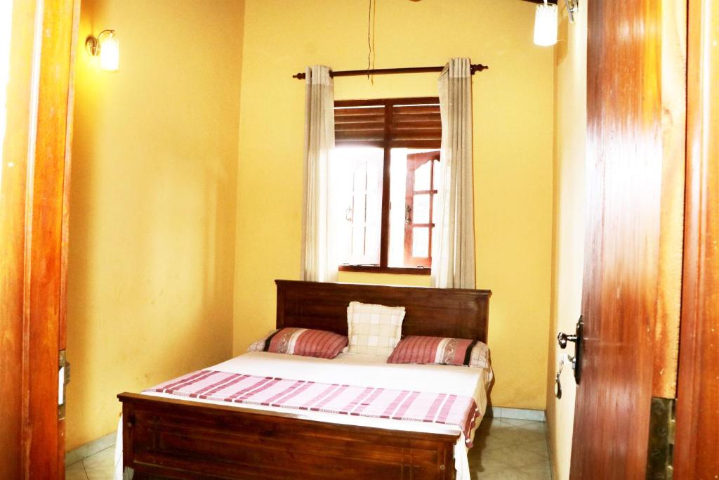 a small bedroom with a bed with a window at Ariyadasa Guest House in Galle