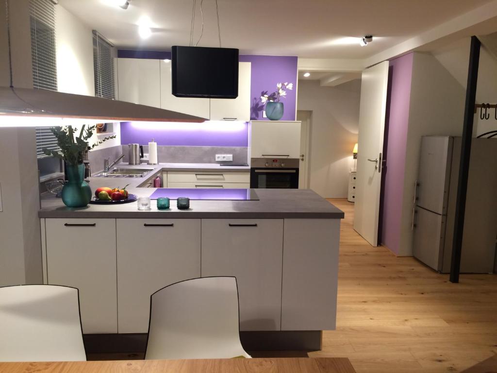 a kitchen with white cabinets and purple walls at Pantone Ultra in Dossenheim