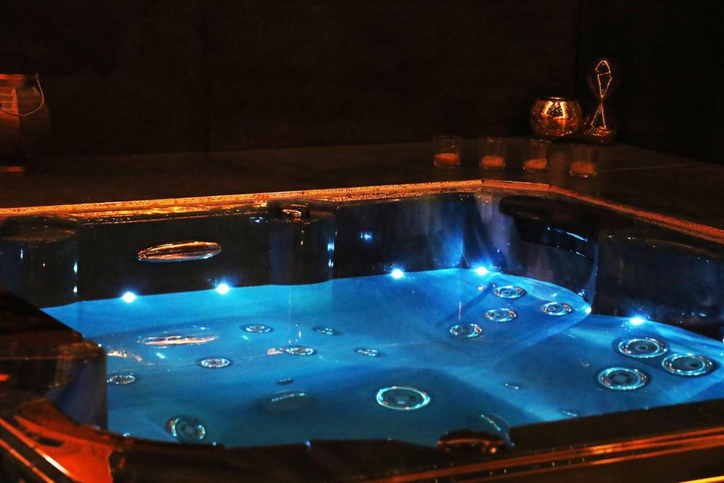 une baignoire bleue avec des lumières au-dessus dans l'établissement La Maison des Charpentiers, à Zimmerbach