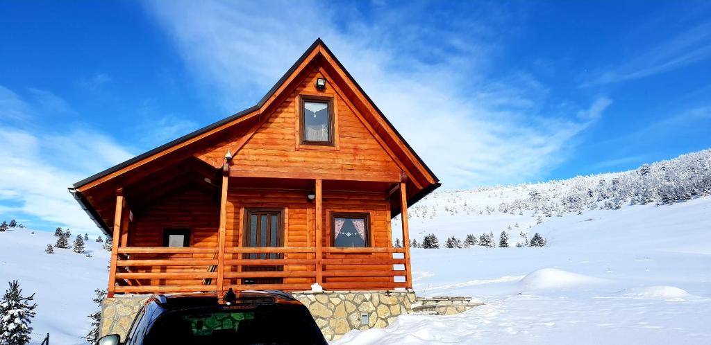 Ljubiš的住宿－Lodge Ljubiska Previja，雪地里的小木屋,前面有车
