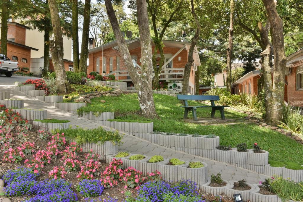 um parque com um banco e flores e árvores em Hotel Pequeno Bosque em Gramado