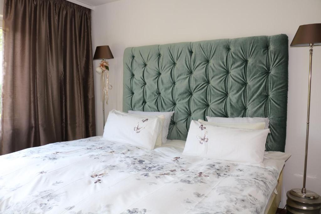 een bed met een groen gewatteerd hoofdeinde en witte kussens bij Happy Homes in Haiger in Haiger
