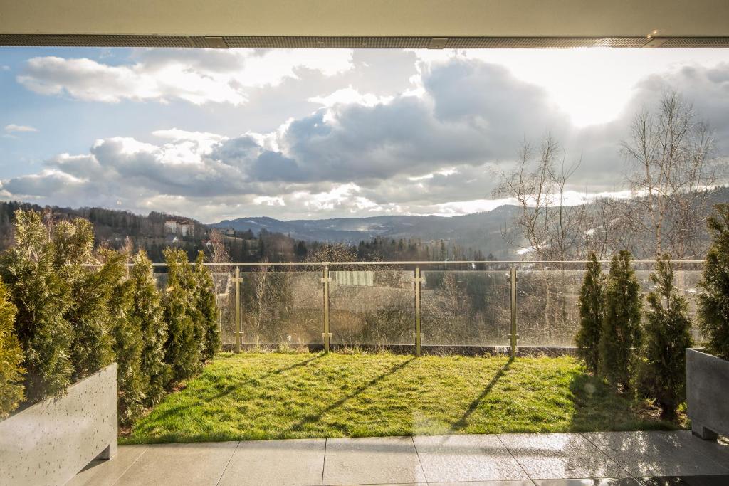 a view of a garden with a fence and mountains at ApartWisła in Wisła