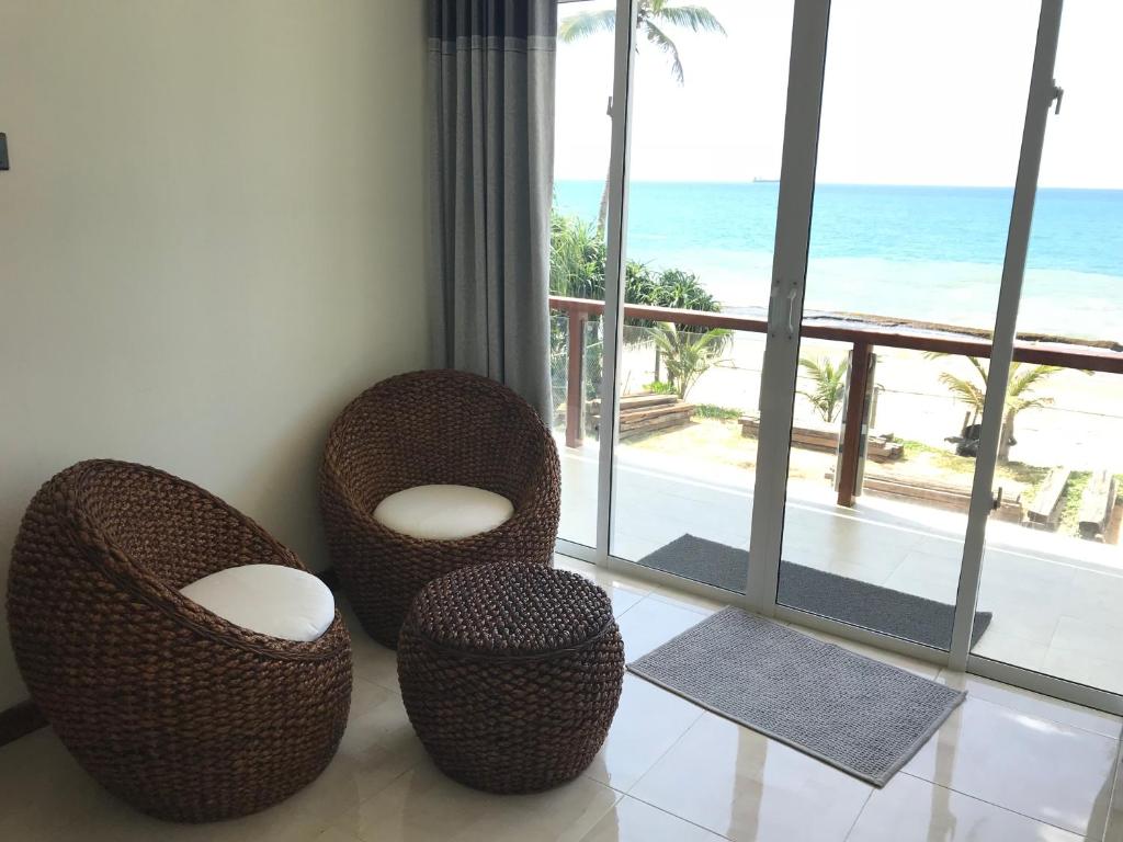 Zimmer mit 2 Stühlen und Meerblick in der Unterkunft Villa Sanará Uswetakeyyawa Beach in Uswetakeiyawa