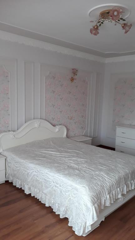 a white bed in a white bedroom with a ceiling at Truskavets Elit Apartment in Truskavets