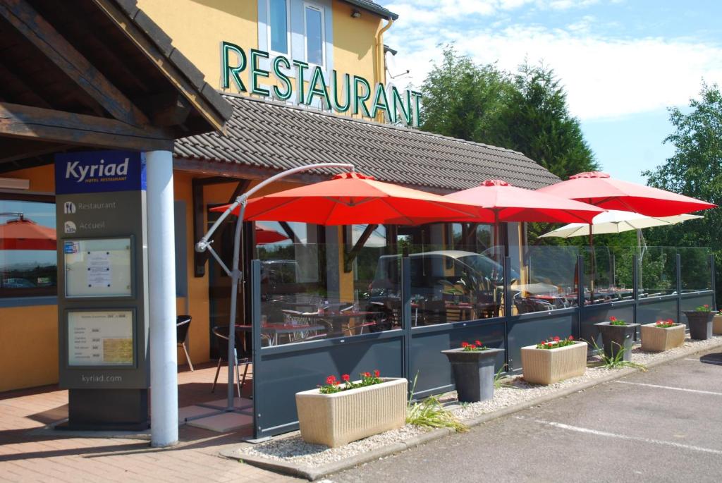 a restaurant with red umbrellas in front of a building at Kyriad Evreux - Netreville in Évreux