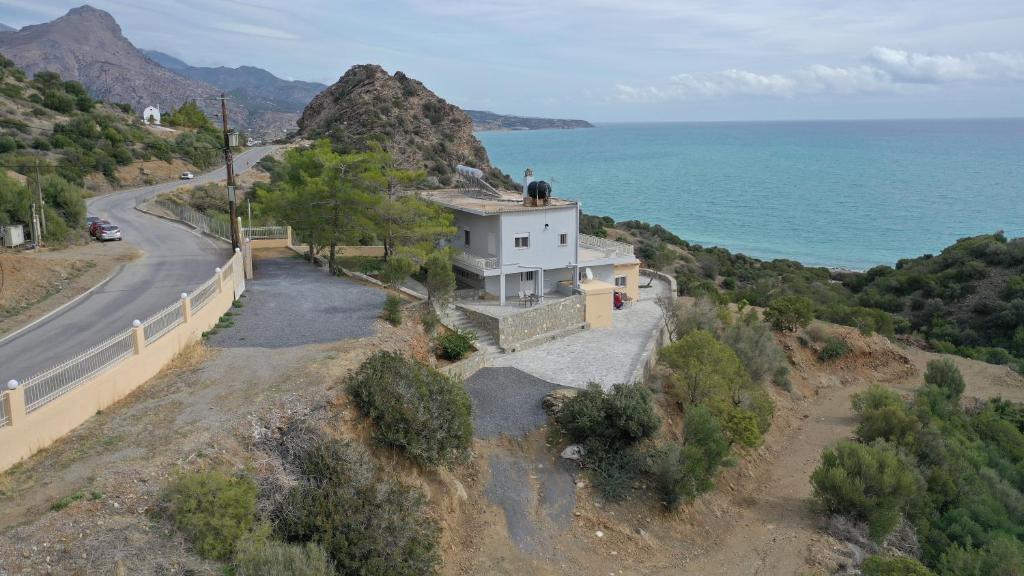 a house on the side of a hill next to the ocean at Skouros Villa in Kastrí