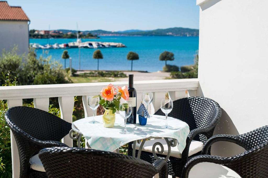 a table with wine glasses and flowers on a balcony at Apartmani Labud in Sukošan