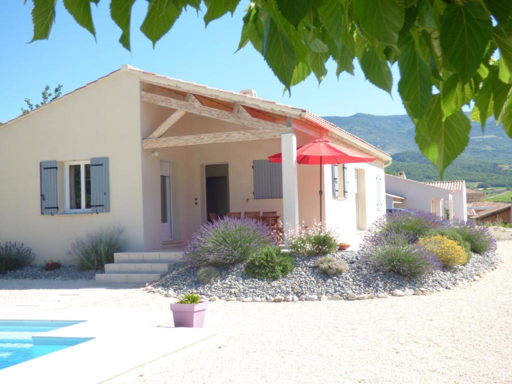 a house with a red umbrella in front of it at LES HAUTS DE JALLIA in Sainte-Jalle