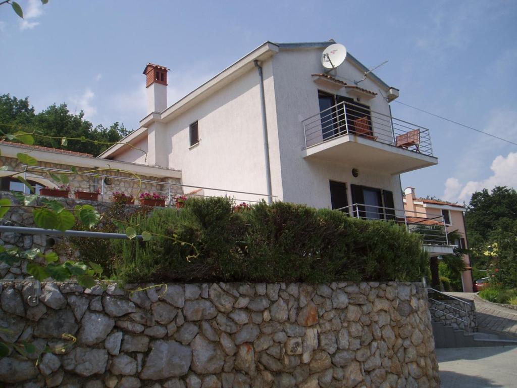a large white house with a clock on top of a stone wall at Apartments Villa Cerić in Lovran