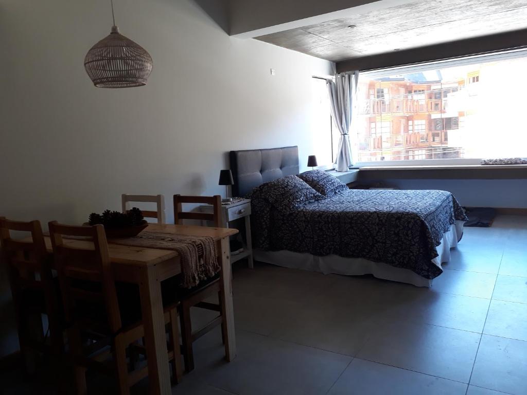 1 dormitorio con cama, mesa y ventana en Edificio UMAIN en San Martín de los Andes