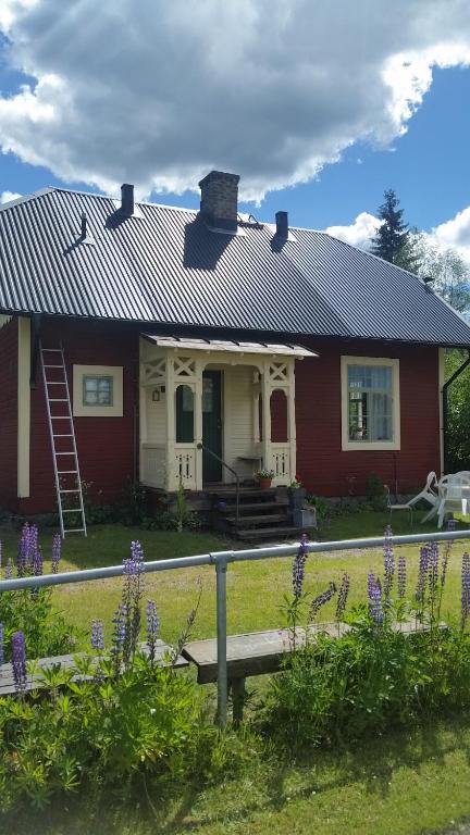 una casa roja con flores púrpuras delante de ella en Holsby banvaktarstuga en Ransäter