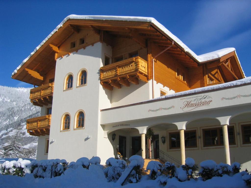 un gran edificio con nieve en el suelo en Landhaus & Appartementhaus Haussteiner, en Dorfgastein