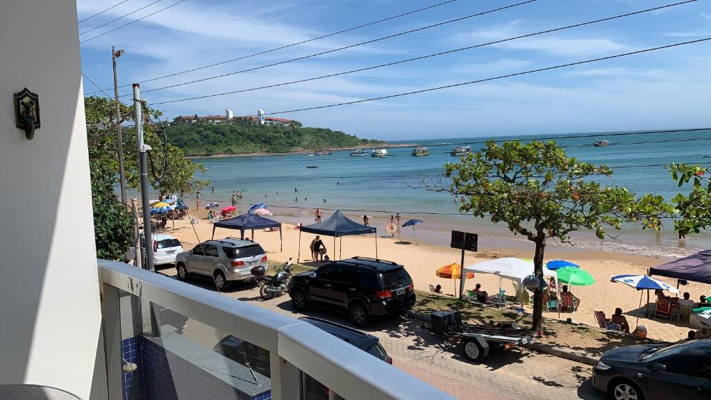 een uitzicht op een strand met auto's en parasols bij Apartamento 3 quartos Beira Mar in Anchieta