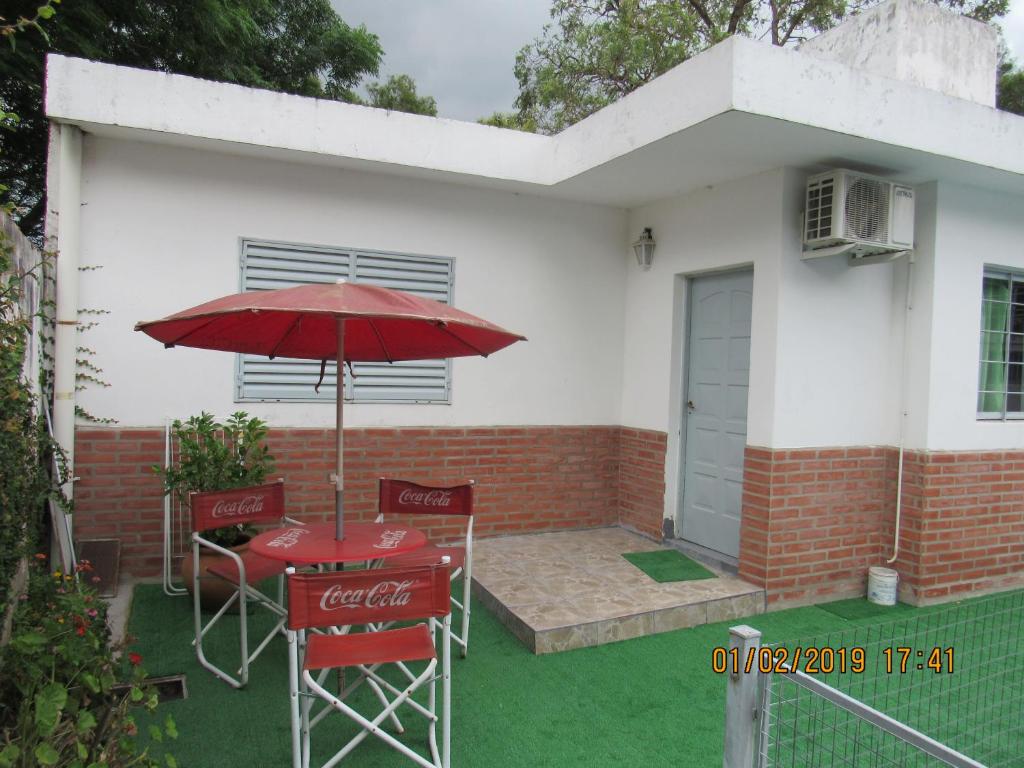 una mesa roja y sillas con sombrilla frente a una casa en Departamento Carlos Paz en Villa Carlos Paz