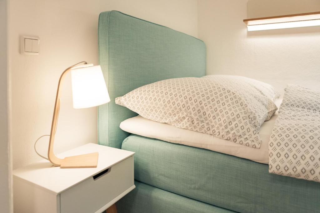 a bed with a green headboard next to a table with a lamp at Smaaland in Flensburg