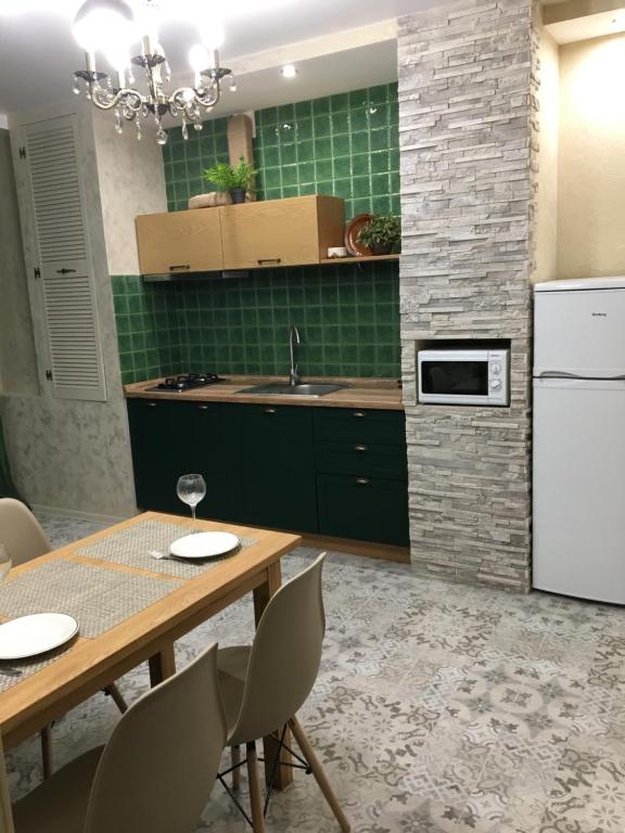a kitchen with a wooden table and a white refrigerator at Софиевский квартал in Petropavlovskaya Borshchagovka