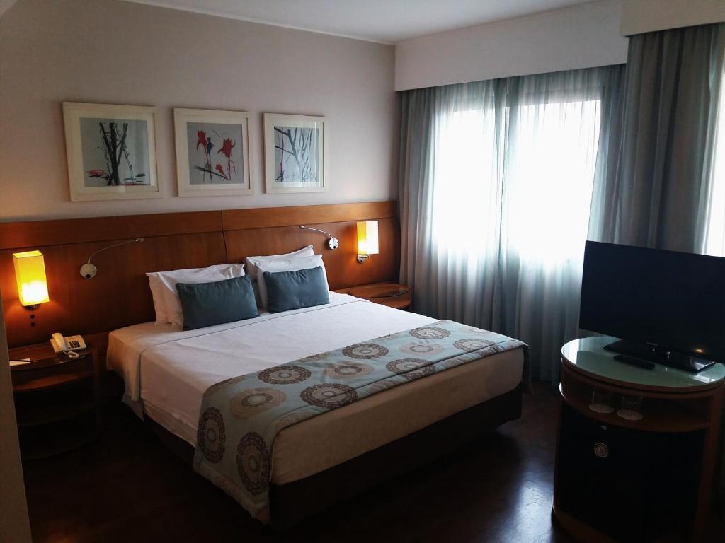 Habitación de hotel con cama y TV en Flat Luxo Moema, en São Paulo