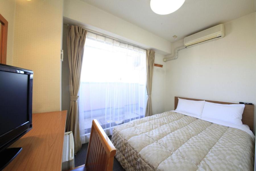Schlafzimmer mit einem Bett, einem TV und einem Fenster in der Unterkunft Hotel Musashino no Mori in Fuchu