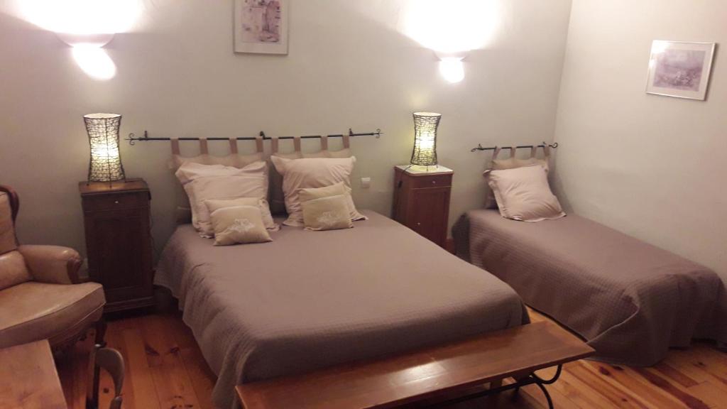 two beds in a room with two lamps and a chair at Chambres d'hôtes Belle Occitane in Tarascon-sur-Ariège