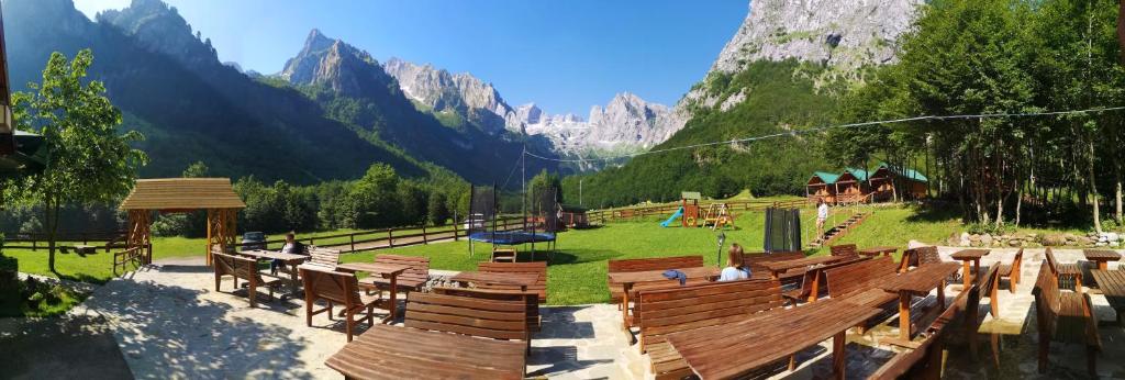 a park with wooden benches and a view of a mountain at Bungalows Katun Maja Karanfil in Gusinje