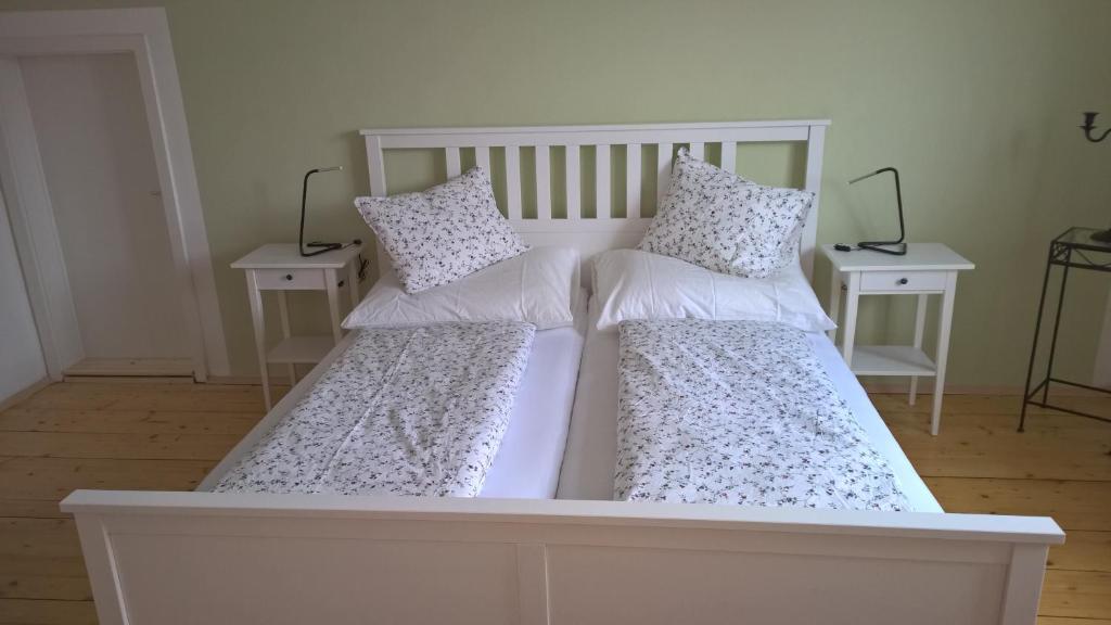 a white bed with two pillows and two tables at Rosenappartement-Deutschkreutz in Deutschkreutz