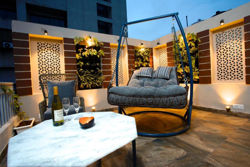 Un patio con un columpio y una mesa y una botella de vino. en Blue Beds Hostel, en Jaipur