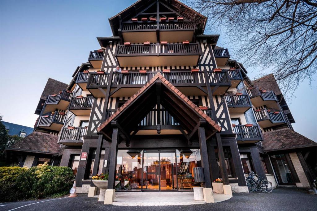 a large building with balconies on top of it at Best Western Plus Hostellerie Du Vallon in Trouville-sur-Mer