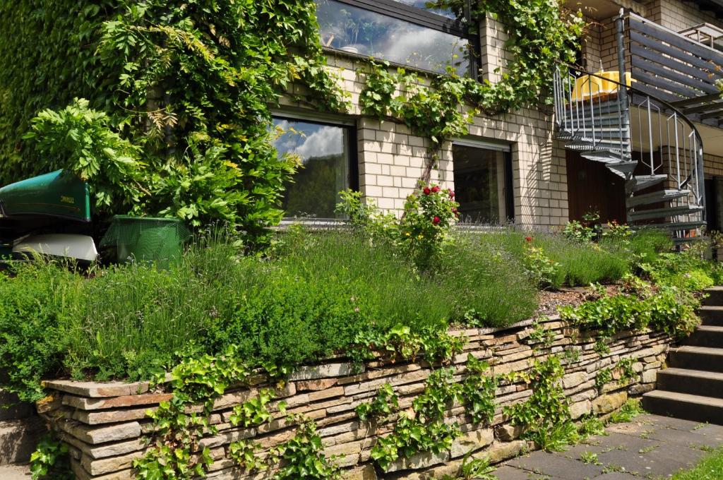 a brick retaining wall in front of a house with plants at Ferienwohnung Raiser in Hagen