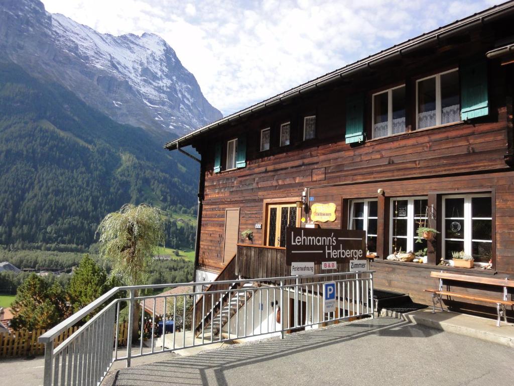a building with a sign on it with mountains in the background at Lehmann's Herberge Hostel in Grindelwald