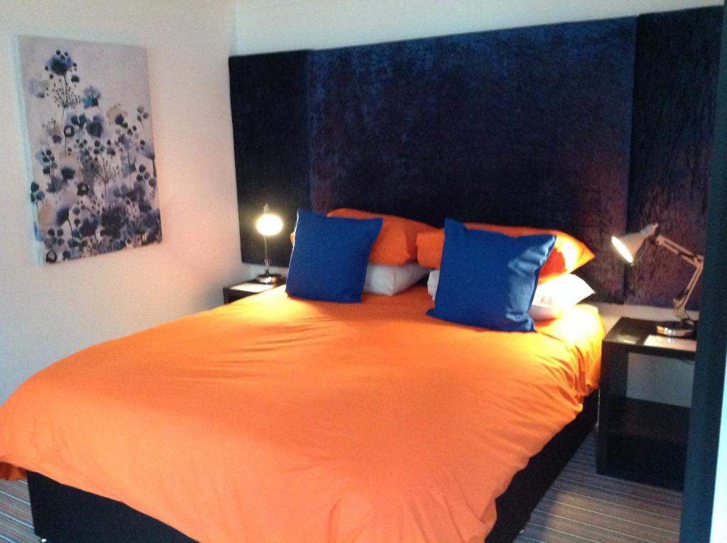 a bedroom with a large orange bed with blue pillows at The old post office in Bicester