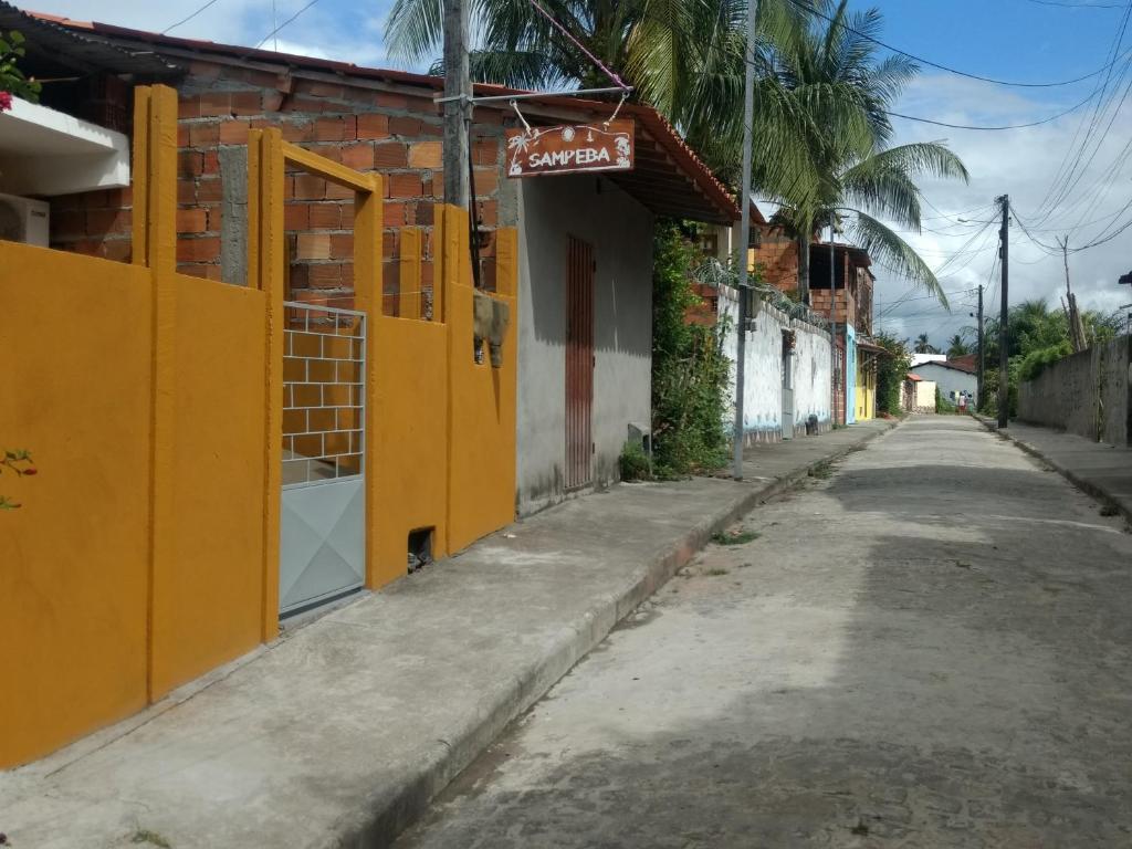 an empty street with a yellow door and a building at Sampeba in Ilha de Boipeba