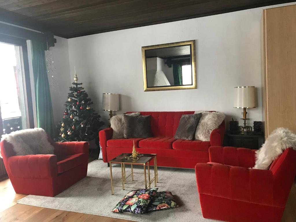 a living room with a red couch and a christmas tree at TOP LOCATION - Klosters center - 130m distance to ski lift Parsenn Gotschnabahn and railway station Klosters Platz - direct connection to Davos in Klosters