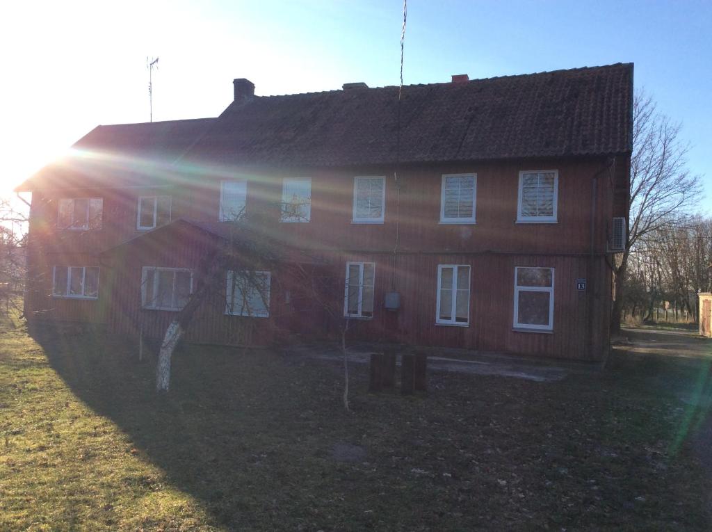 a large wooden house with the sun shining on it at Apartamentai Rusnėje , Nemuno 13 in Rusnė