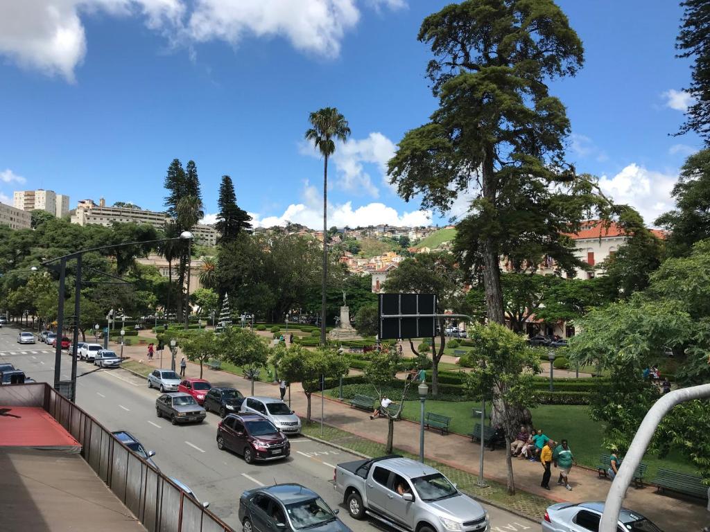 a busy city street with cars parked on the road at Hotel Vila Real Rex in Poços de Caldas