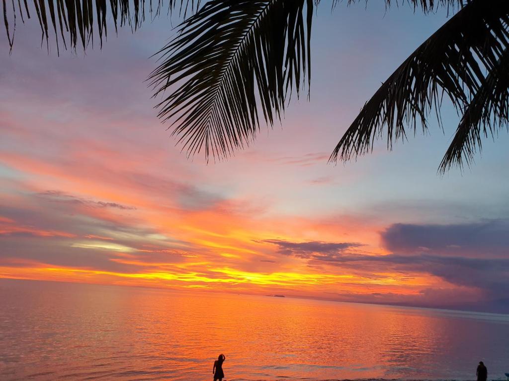 eine Person, die am Strand steht und einen Sonnenuntergang beobachtet in der Unterkunft Isla de Paz Beach Resort in Siquijor