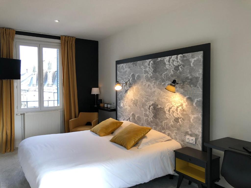 a bedroom with a white bed and a large wall at Hôtel Le Cobh in Ploërmel