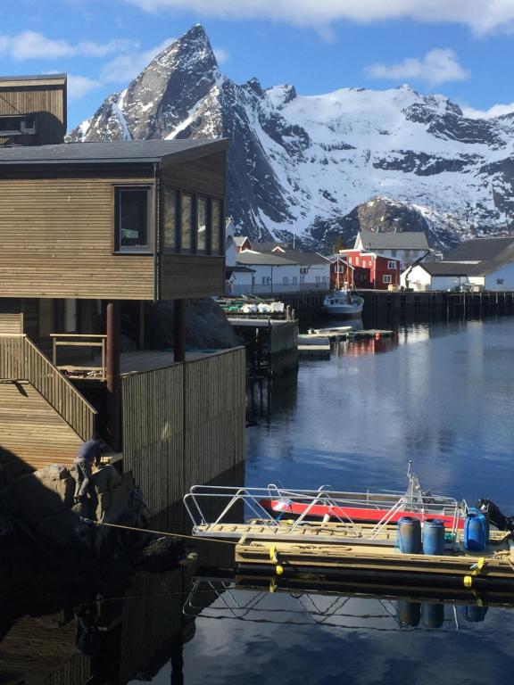 a boat docked at a dock with a snow covered mountain at Lurn Sjøhus in Reine