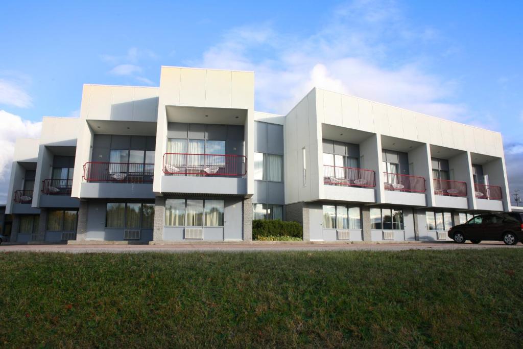 a white building with a car parked in front of it at Motel Chute des Pères in Dolbeau