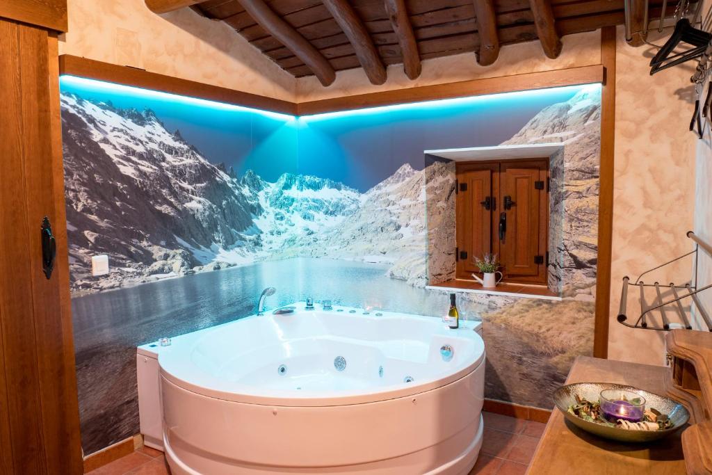 a bath tub in a bathroom with a painting on the wall at Casa Rural El Berrueco in Robledillo