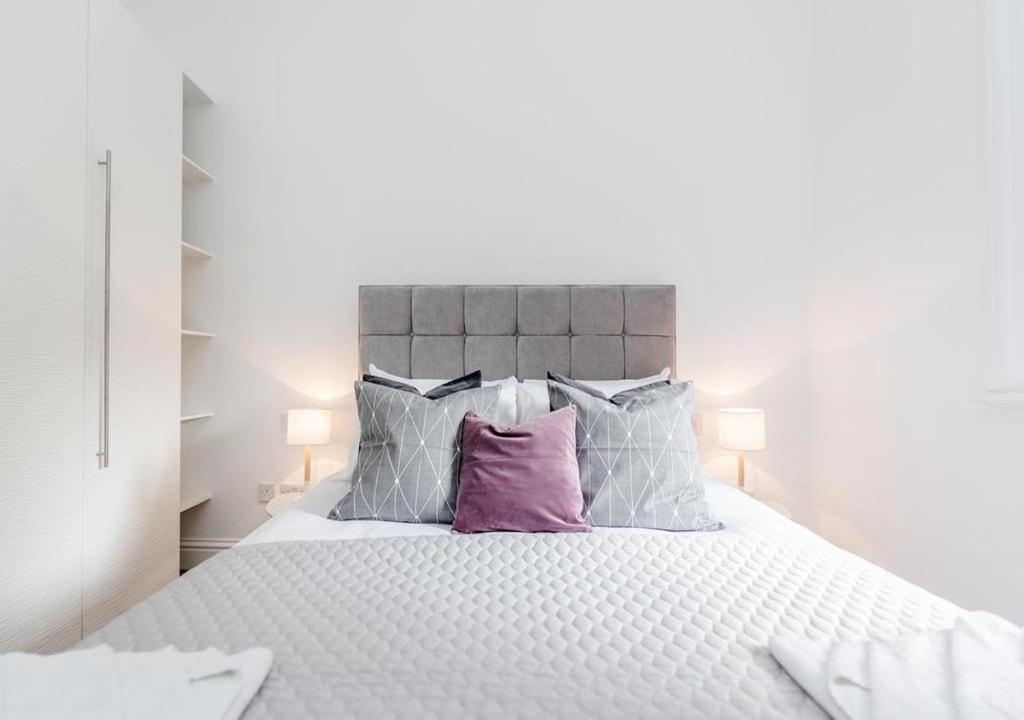 a bedroom with a large white bed with purple pillows at White Piccadilly Luxury Flat in London
