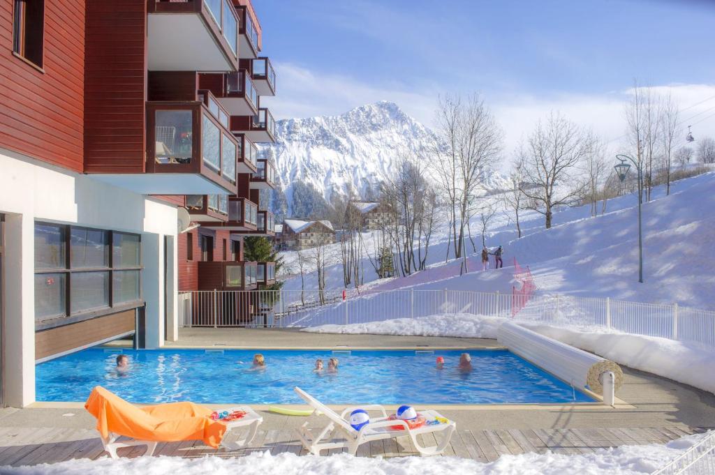 a swimming pool with people in the snow at Résidence Goélia Les Terrasses du Corbier in Le Corbier