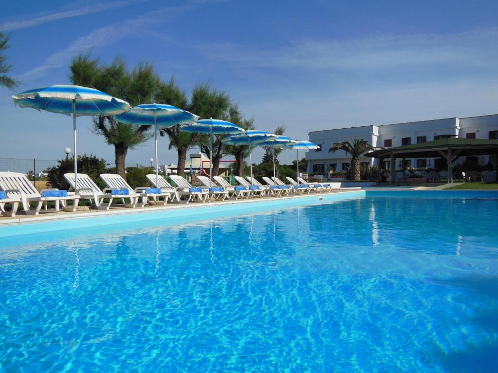a large swimming pool with chairs and umbrellas at Residence Club Barbara in Ostuni