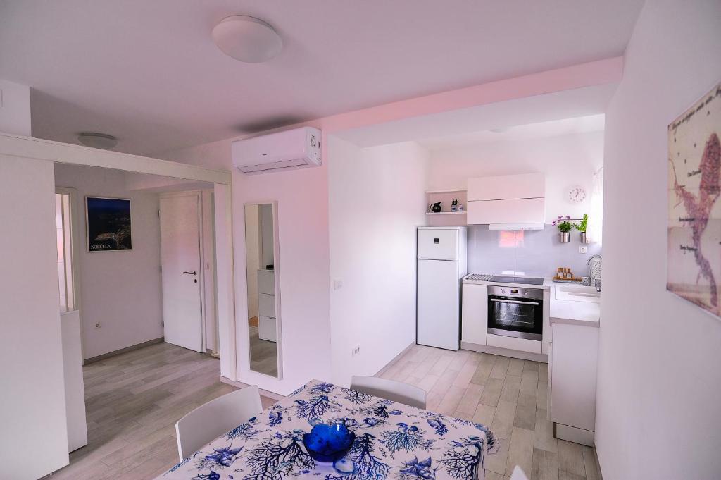 a small white kitchen with a table and a dining room at Apartments An Ni in Korčula