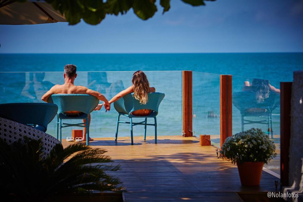 un hombre y una mujer sentados en sillas en la playa en Solar Beach Hotel en Florianópolis