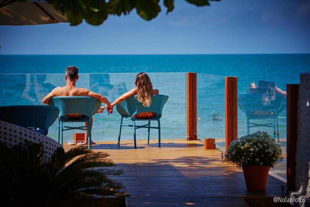 een man en een vrouw zittend in stoelen op het strand bij Solar Beach Hotel in Florianópolis