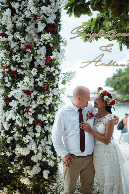 a bride and groom standing in front of a wall of flowers at Ao Cho Grandview Hideaway Resort in Ko Samed