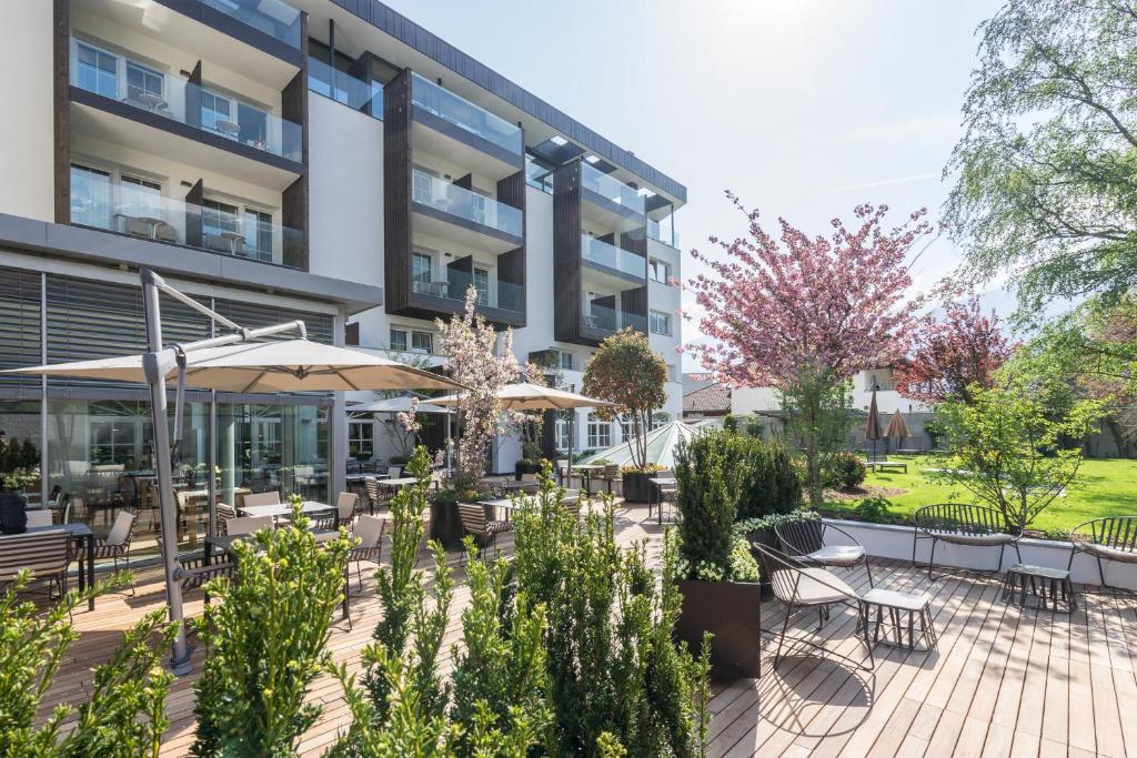 un patio esterno con tavoli e ombrelloni di fronte a un edificio di Vinschgerhof a Silandro