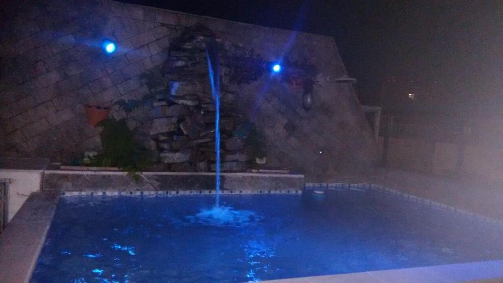 Una fuente de agua en una piscina por la noche en Cobertura Enseada Guarujá, en Guarujá